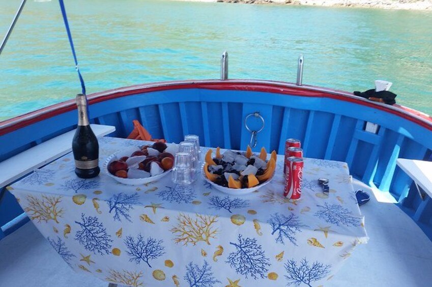 Un bote con una mesa dispuesta con comida y bebidas, rodeado de agua. 3