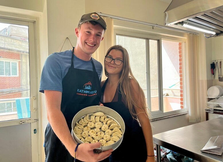 Two people in a kitchen holding a bowl of dumplings. 3
