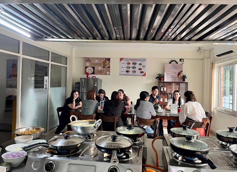 A group of people in a kitchen with cooking equipment and a menu on the wall. 4