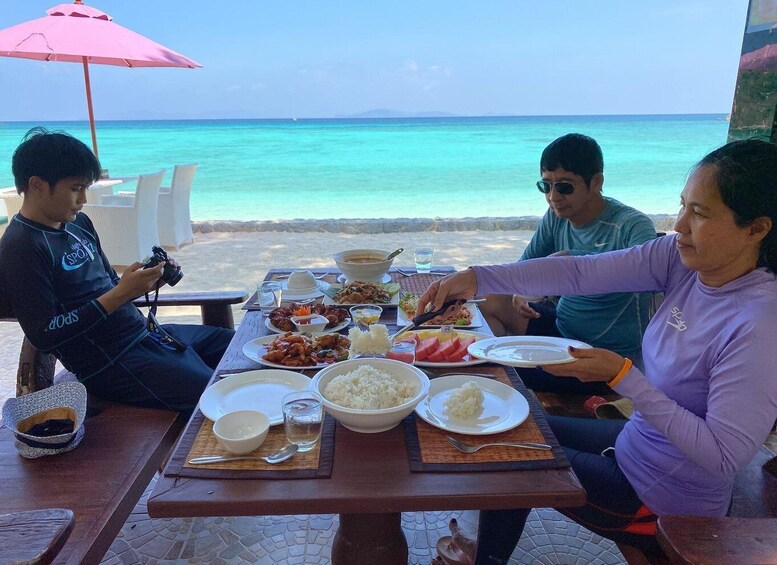 A group of people dining at a table with a view of the ocean. 2
