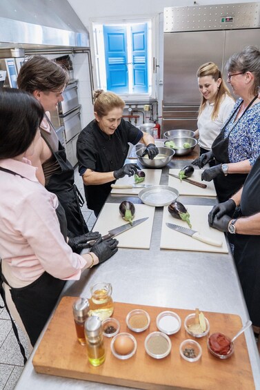 Un grupo de personas preparando comida en una cocina, con diversos ingredientes y utensilios sobre la encimera. 2