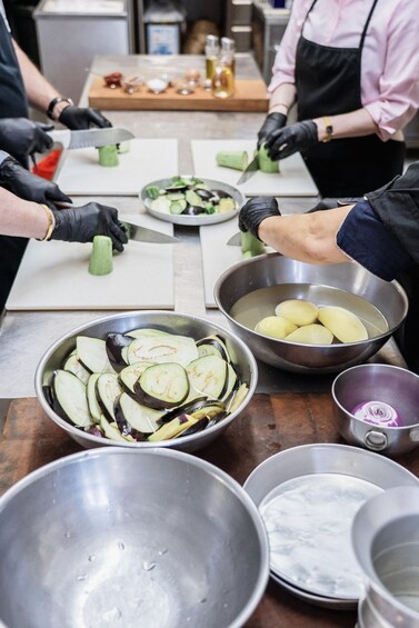 Una cocina con chefs preparando comida, incluyendo verduras y papas en rodajas. 1