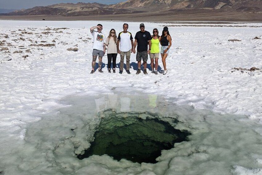 Un grupo de personas de pie sobre un lago congelado con un agujero grande en el hielo. 3