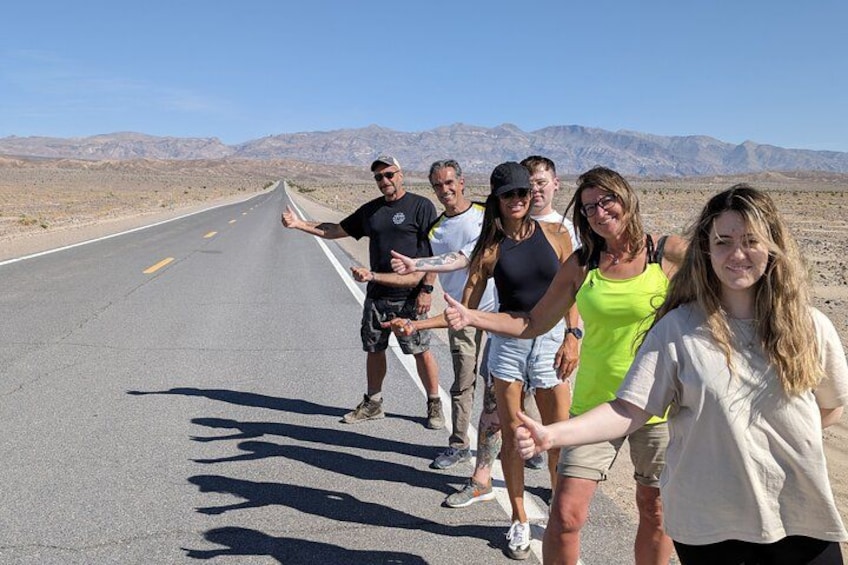 Un grupo de personas de pie en una carretera con un paisaje desértico al fondo. 1