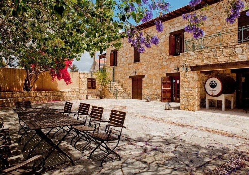 A courtyard with stone buildings, a wooden table with benches, and a barrel outside a building. 3