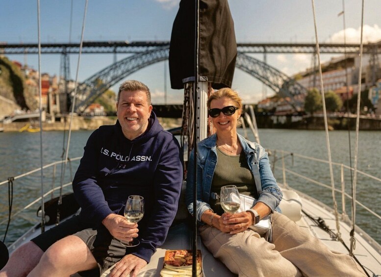 Two people on a sailboat with a bridge in the background. 4