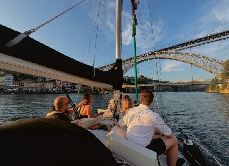 A group of people on a sailboat, a bridge in the background, and a cityscape along the river. 5