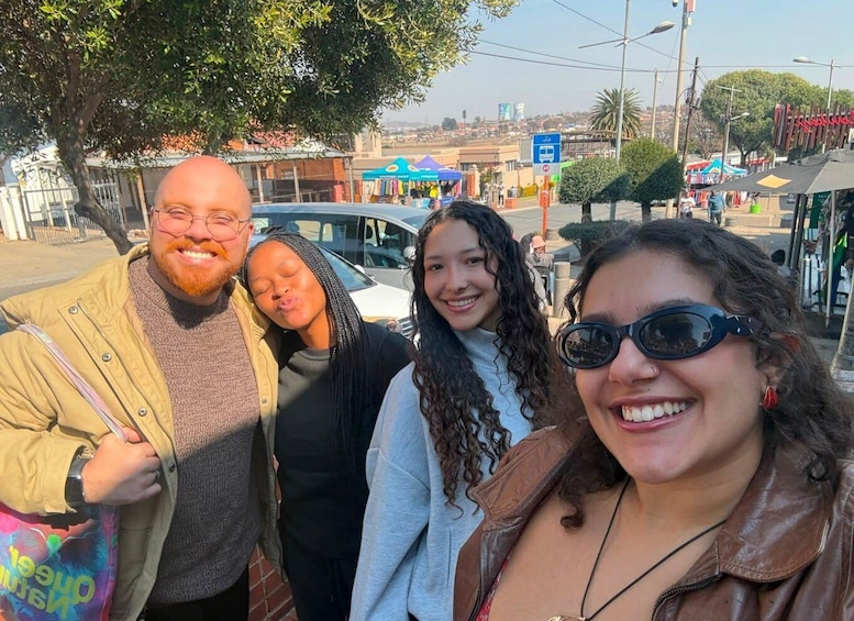 A group of people standing outdoors with a street and shops in the background. 2