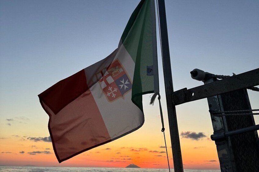 A flag on a flagpole against a sunset backdrop. 4