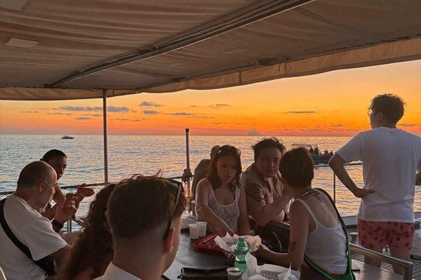 A group of people dining on a boat with a sunset in the background. 5