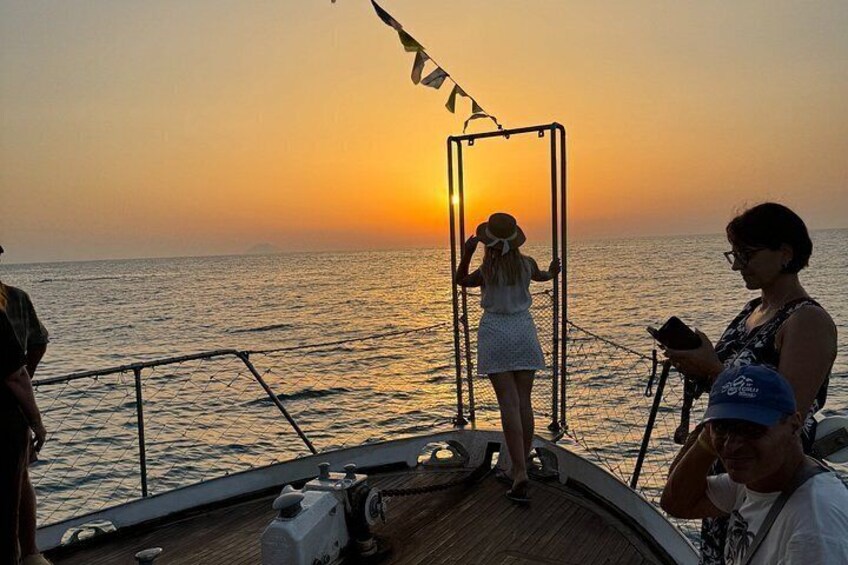 A sunset over the ocean with people on a boat. 1