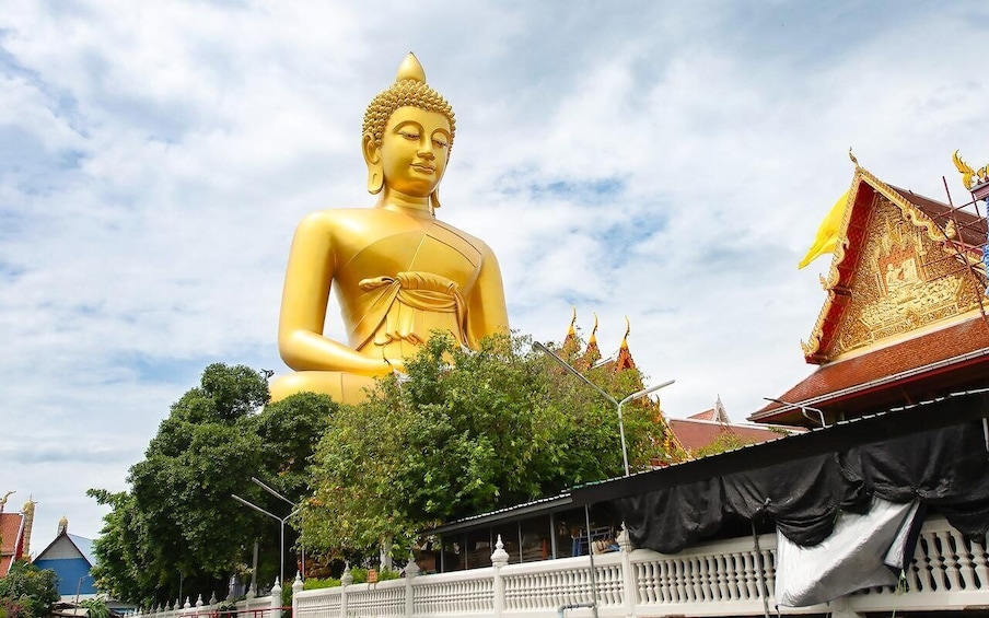 A large golden Buddha statue, surrounded by traditional architecture and lush greenery. 1