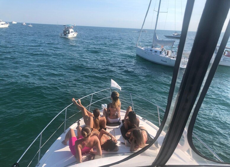 Eine Gruppe von Menschen auf einem Segelboot im Ozean, im Hintergrund sind weitere Boote zu sehen. 5