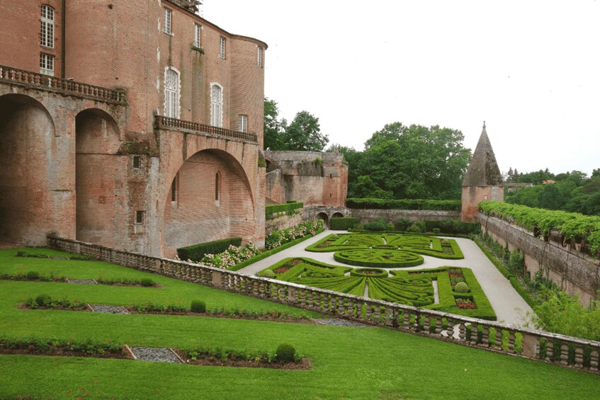 A historic building with a symmetrical garden and a tower. 2
