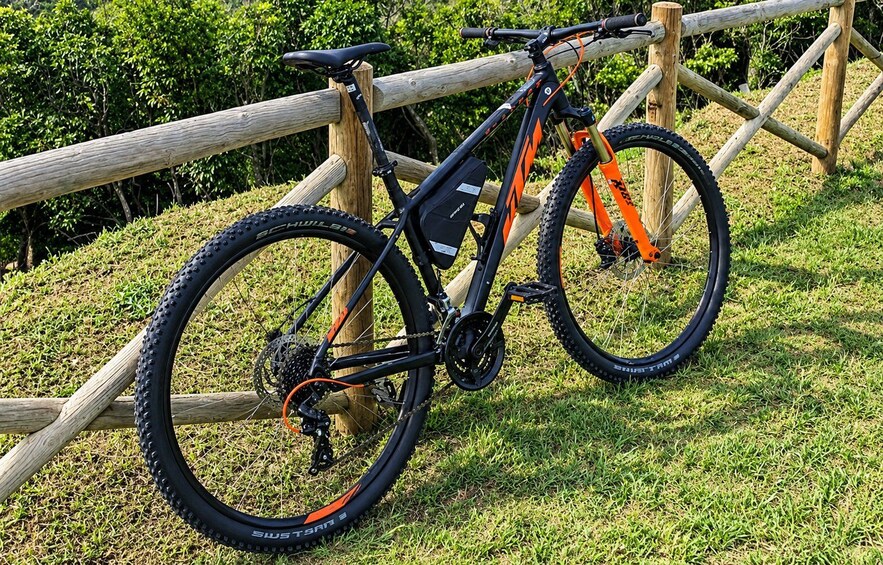 Ein Mountainbike mit orange-schwarzen Farben, schwarzen Reifen und einem Holzzaun im Hintergrund. 5
