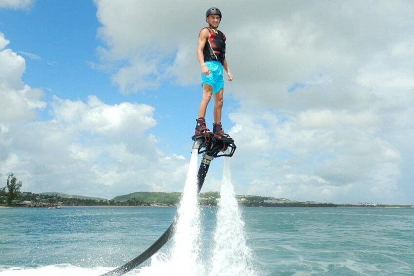 A person water skiing on a clear day with a body of water, a boat, and distant landforms. 1