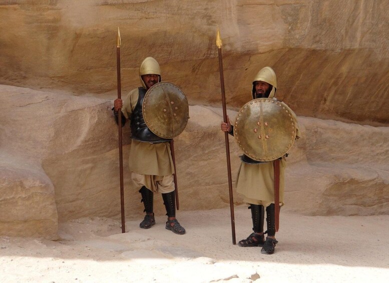Two individuals in historical armor holding shields and spears, standing in a rocky terrain. 5