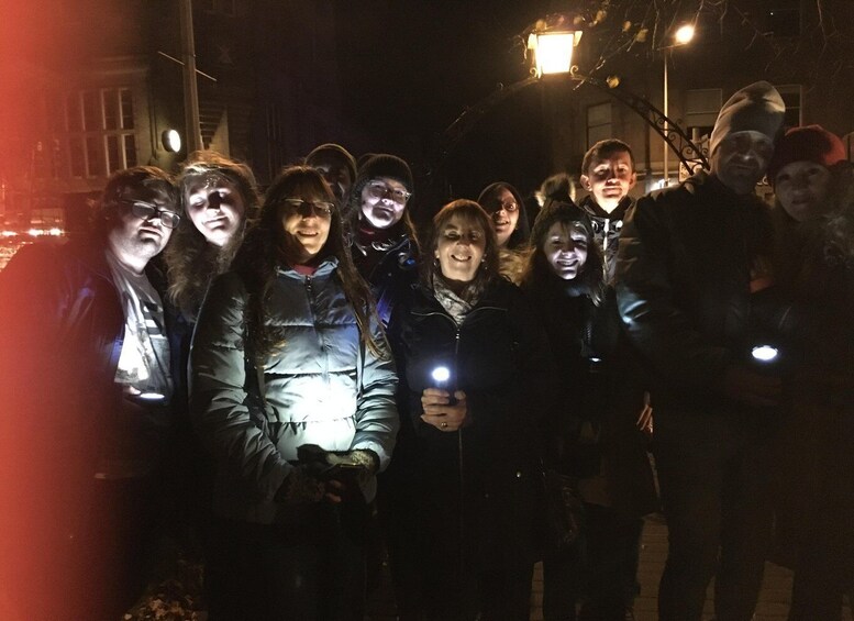 A group of people standing together at night, some holding lights. 3