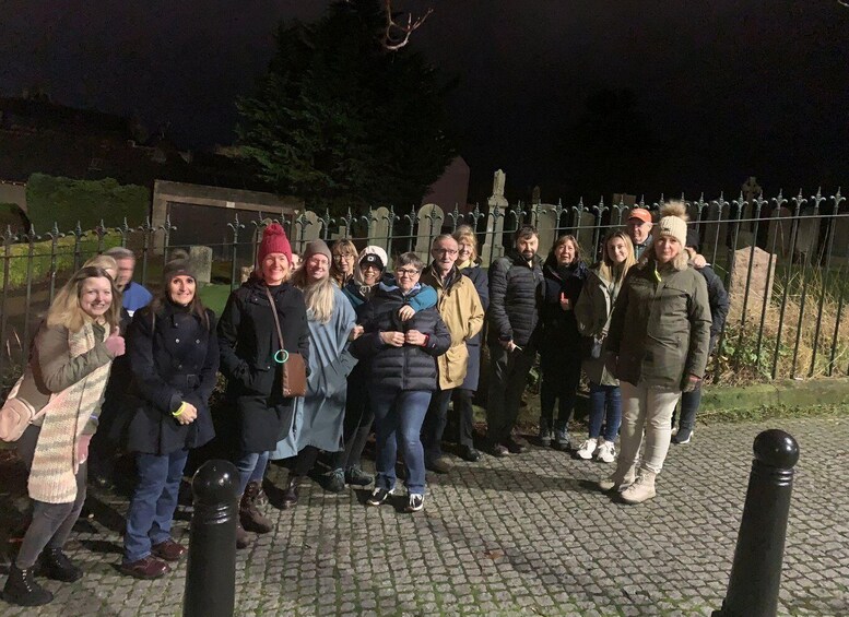 A group of people standing on a cobblestone path at night. 1