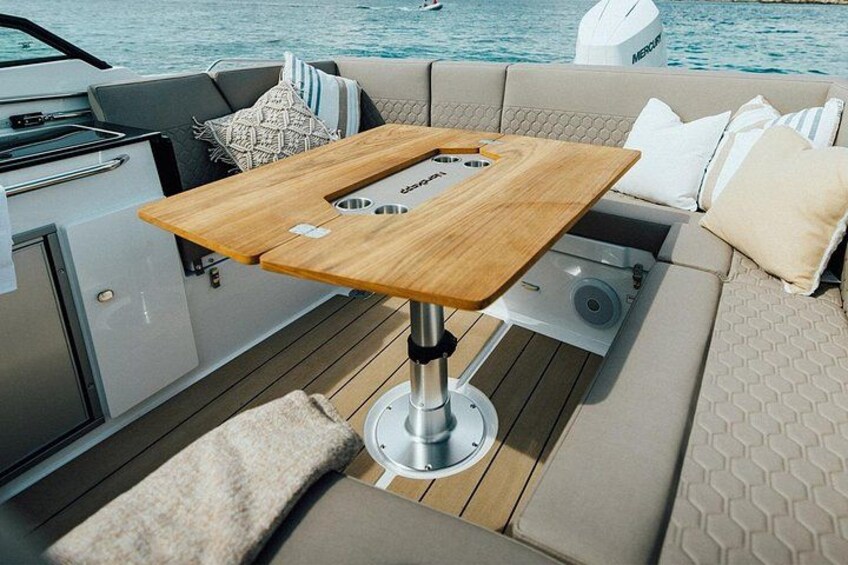 Däcket på en lyxyacht med ett träbord, bekväma sittplatser och utsikt över vattnet. 5