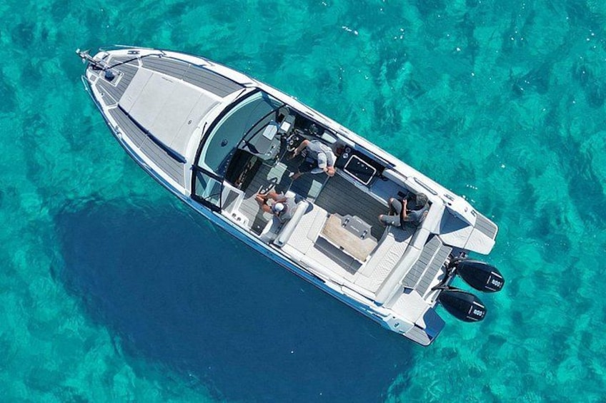 Un bateau à moteur blanc, doté d’un pont couvert, navigue sur des eaux turquoise et limpides. 1