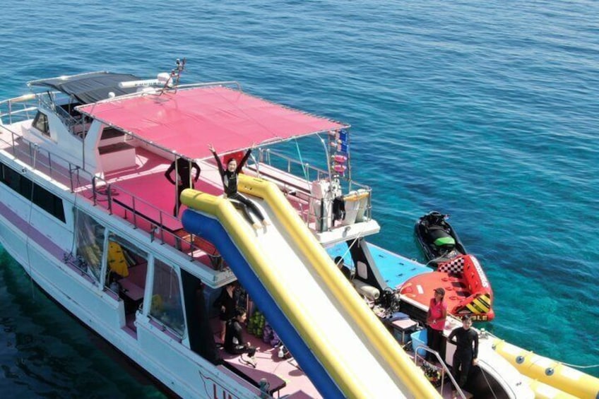 A boat with a red canopy, a yellow slide, and a red and blue jet ski. 3