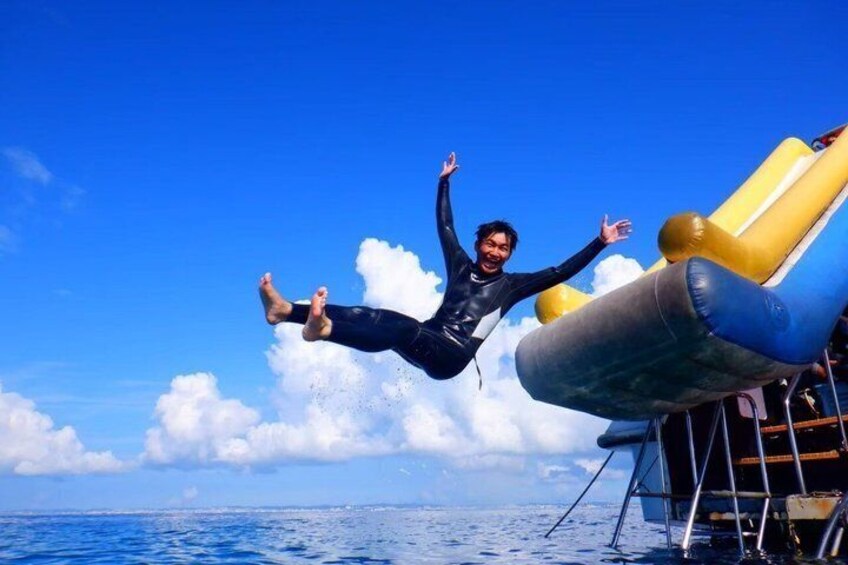 A person in a wetsuit jumping off a boat into the ocean. 2