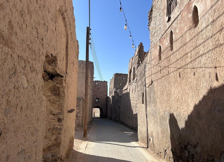 A narrow alleyway with stone walls, a paved path, and a clear blue sky. 5