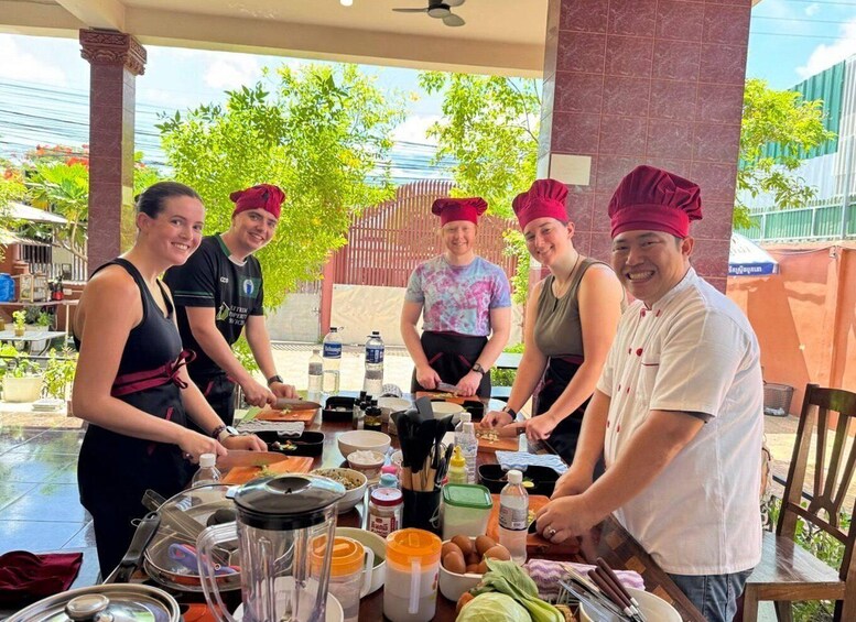 A group of people preparing food outdoors with a table full of ingredients and cooking utensils. 2
