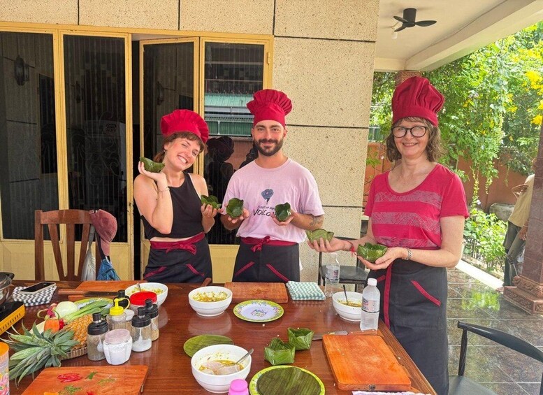 Three people in chef hats standing at a table with food ingredients and cooking utensils. 3