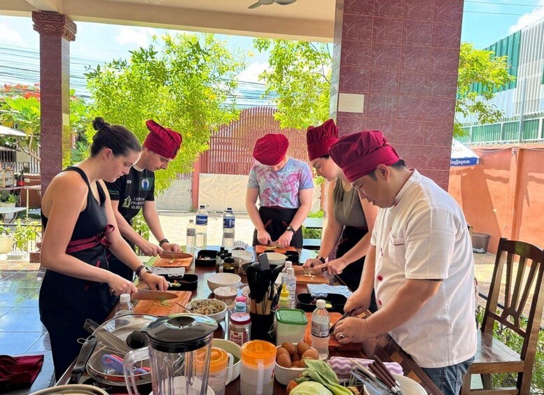 A group of chefs preparing food outdoors with a table full of ingredients and cooking utensils. 1