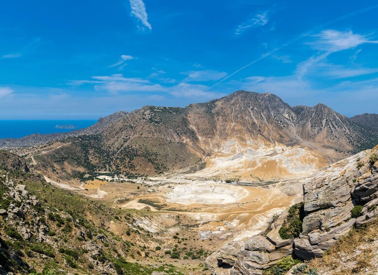 A mountainous landscape with a valley, rocky outcrops, and a distant coastline. 5