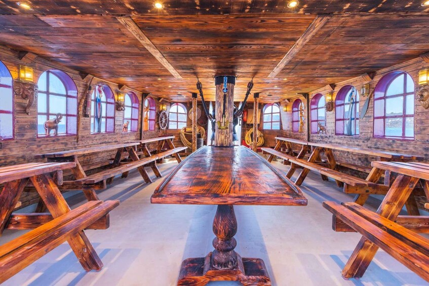 A long wooden table with benches, arched windows, and wooden beams on the ceiling. 5