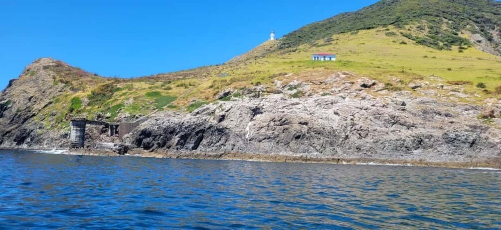 Un paysage côtier avec un phare, des falaises rocheuses et un petit bâtiment situé sur une colline. 5