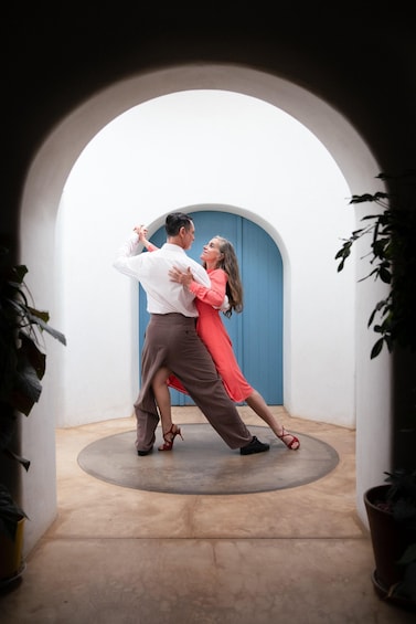 Un couple danse dans un espace circulaire, avec une porte bleue en arrière-plan. 1