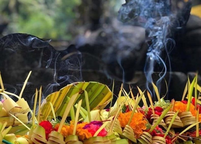 A ritual with smoke rising from offerings in banana leaves. 1
