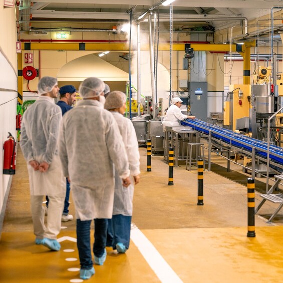 A factory with workers in protective gear walking along a conveyor belt. 2