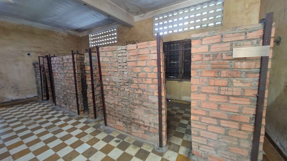 A corridor with brick walls, a checkered floor, and metal gates. 5