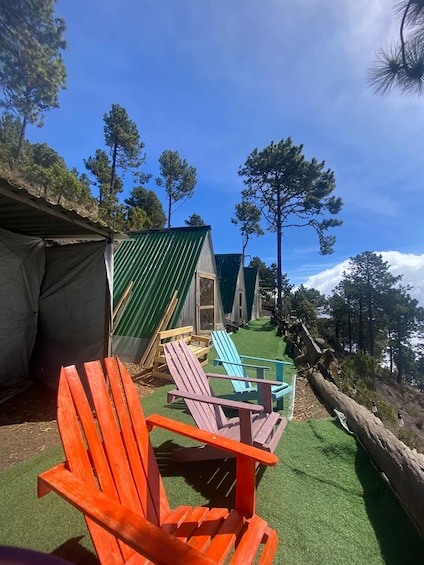 A campsite with green-roofed cabins, a wooden chair, and a log fence. 3