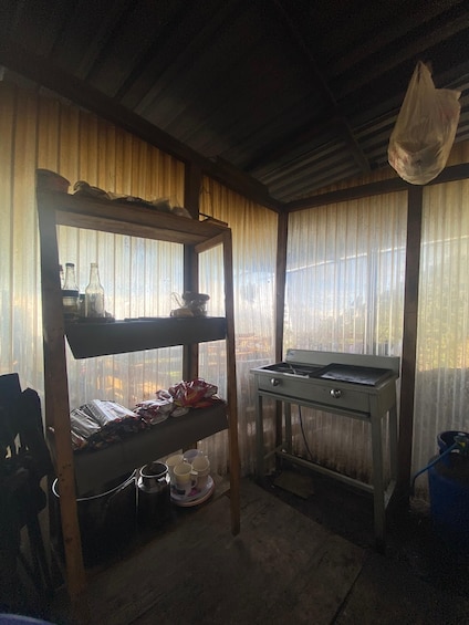 A rustic kitchen with wooden shelves, a gas stove, and a window with a view. 2
