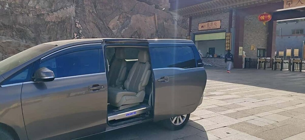 A silver minivan parked in front of a building with Chinese characters. 3