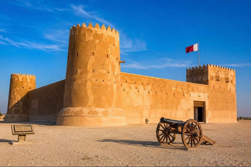 Un’antica fortezza con due torri imponenti, una bandiera e un cannone in primo piano. 2