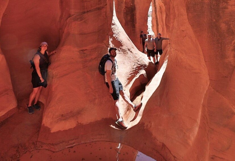 A person climbing a red rock formation with others in the background. 1