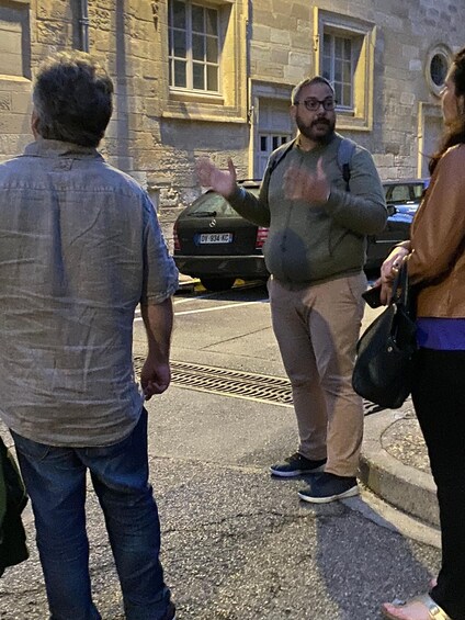 Three people standing on a street with a building in the background. 2