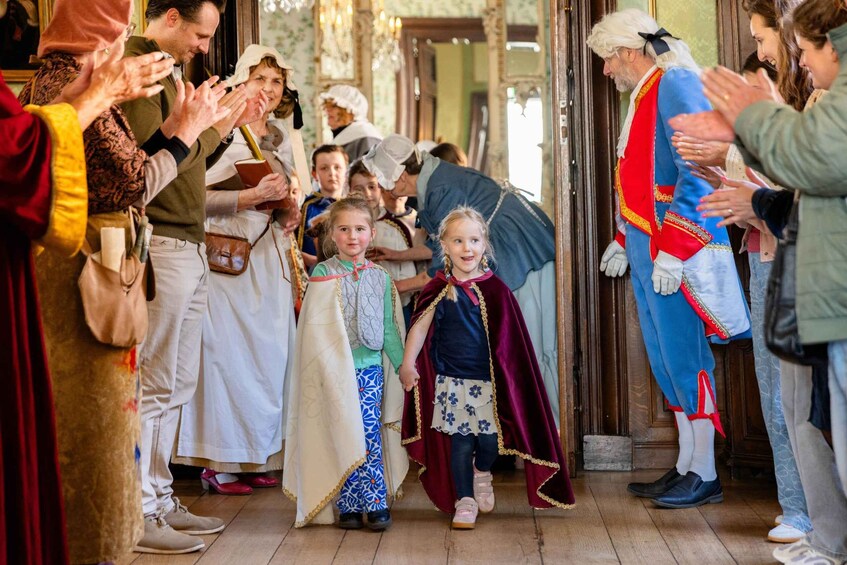 A group of people in historical costumes, including a man in a blue and red outfit, and children in medieval attire. 5