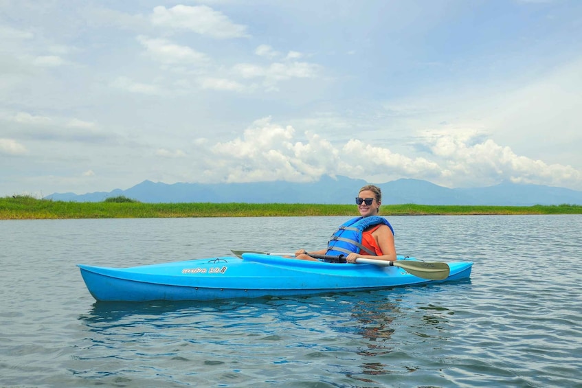 A person kayaking on a calm body of water with mountains in the background. 2