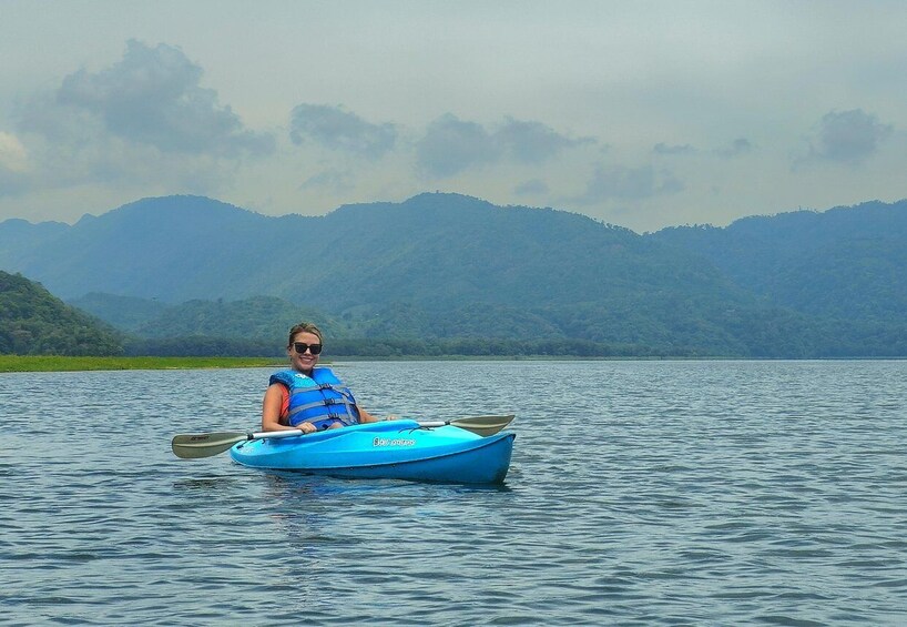 A person kayaking on a calm lake with mountains in the background. 1