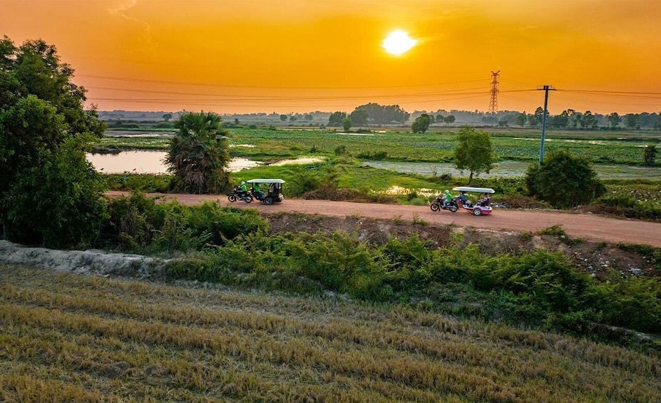Paisaje rural con camino de tierra, campos, una masa de agua y un atardecer. 2