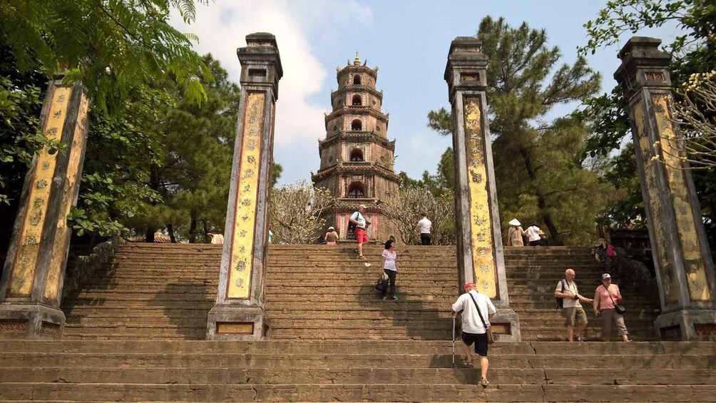 A temple with a multi-tiered pagoda, stone steps leading up to it, and people ascending the steps. 3