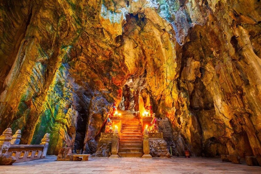 A cave temple with a central altar, stone steps, and statues. 2